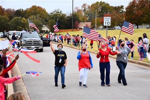 Four Columbia Elementary teachers leading parade carrying flags 